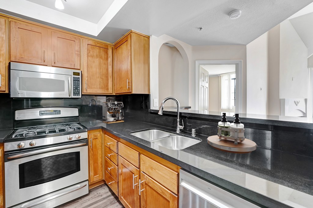 A kitchen with wooden cabinets and a black countertop. at Burton, Los Angeles