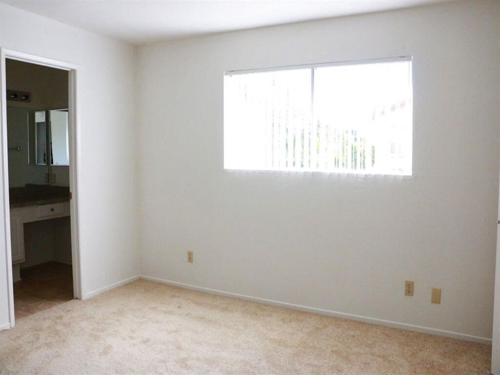an empty room with a large window and carpet