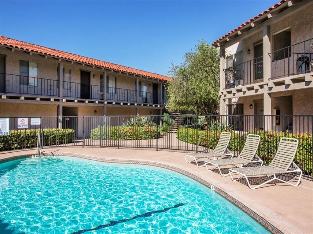 a swimming pool with chaise lounge chairs and a building in the background