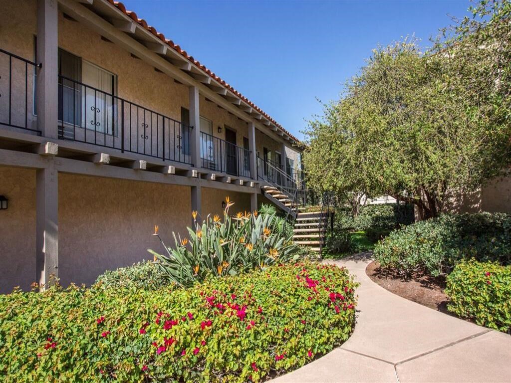a walkway with flowers and trees in the background