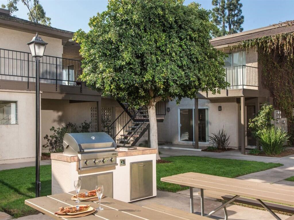 a barbecue grill and picnic table in front of an apartment building