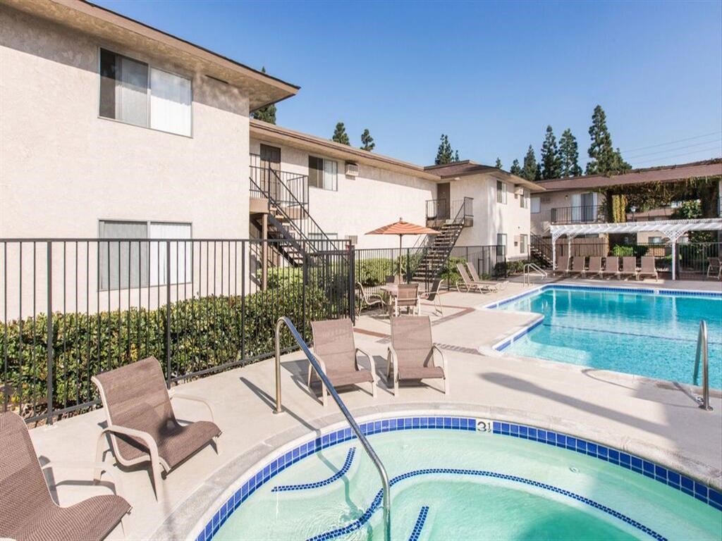 a swimming pool with chairs and umbrellas in front of a building