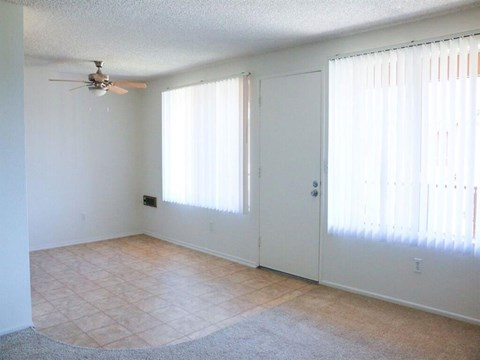 an empty living room with white walls and a ceiling fan
