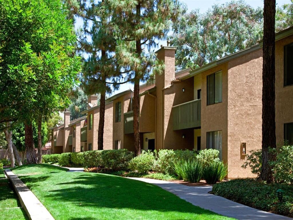a row of apartment buildings with green grass and trees