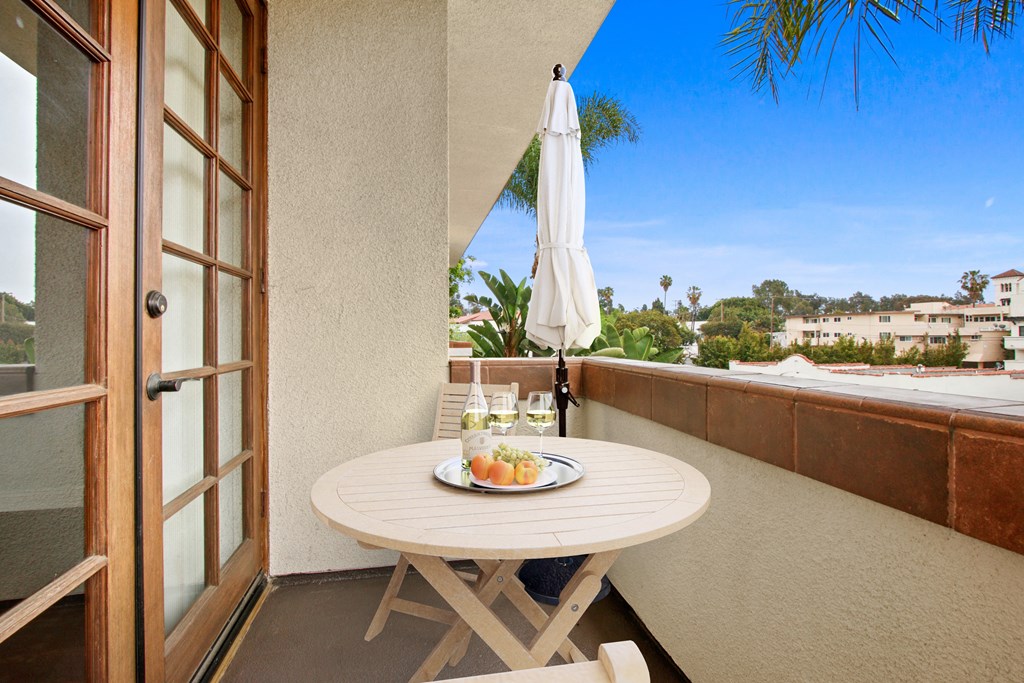 a balcony with a table and an umbrella on a balcony at Darlington Apartments, Los Angeles, CA