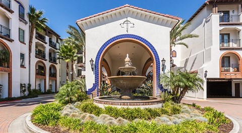 A fountain is in front of a building with a blue and white arch.