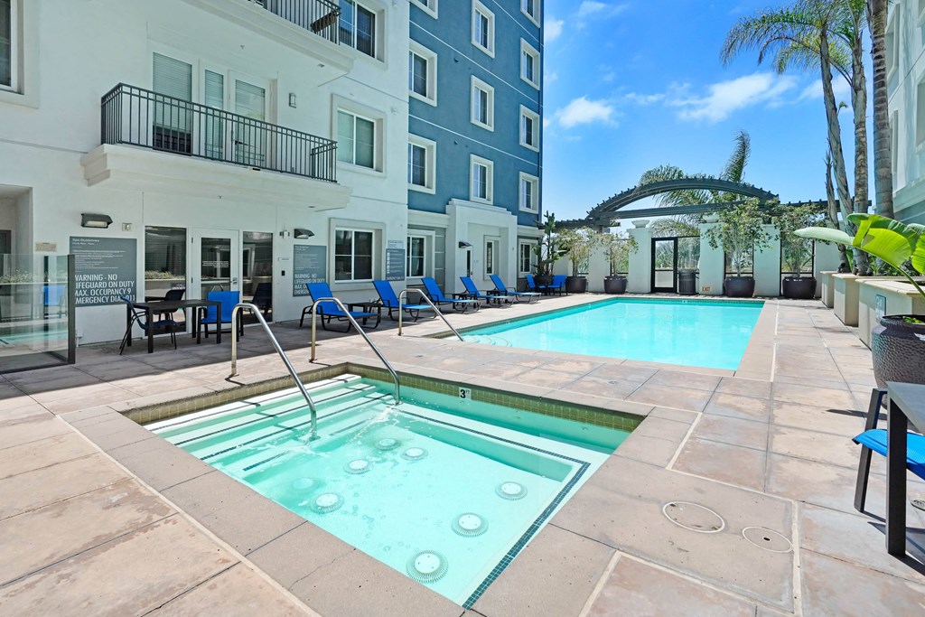 a swimming pool with blue chairs and a blue building in the background