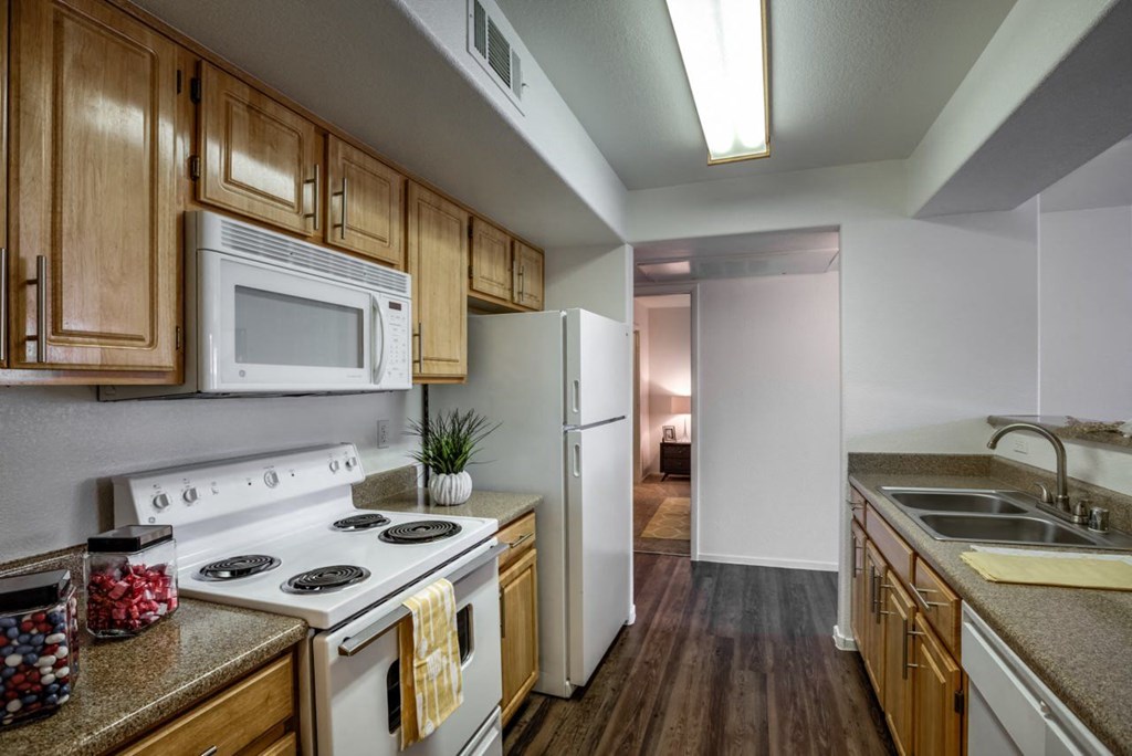 a kitchen with white appliances and wooden cabinets at Bella Terra Apartments, Henderson, NV