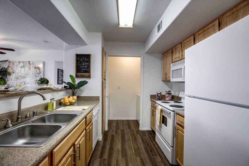 a kitchen with white appliances and wooden cabinets at Bella Terra Apartments, Henderson, 89012
