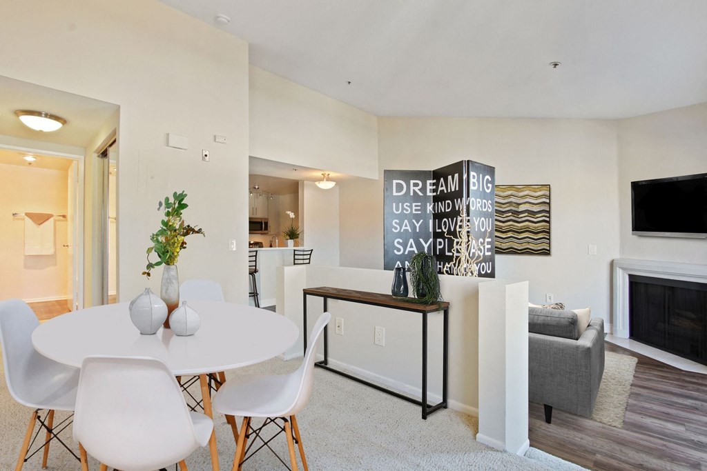 a dining area with a white table and chairs and a fireplace in the background at Palm Royale Apartments, California, 90034