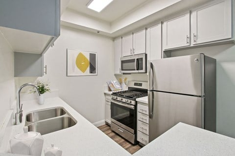 a kitchen with white cabinetry and stainless steel appliances at Palm Royale Apartments, California, 90034