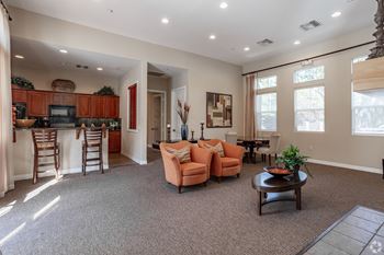a living room with a kitchen in the background and a couch and chairs in the foreground