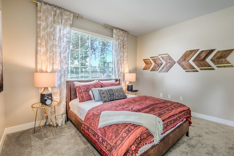 A bedroom with a large bed and a window with curtains.