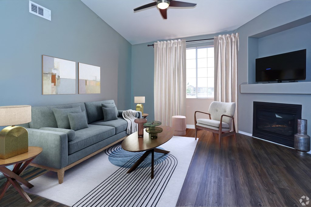 A living room with a grey couch, a fireplace, and a ceiling fan at Milan Apartment Townhomes, Las Vegas, NV, 89183