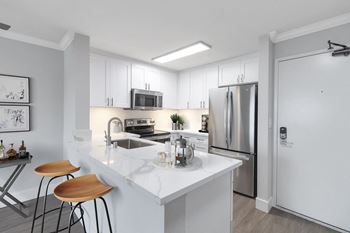 a kitchen with a white counter top and a stainless steel refrigerator at Nobel Court, San Diego, California