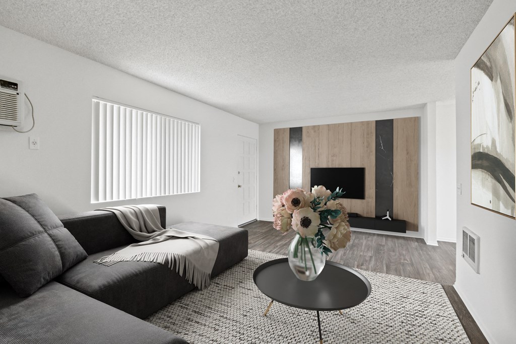 a living room with a black couch and a table with flowers