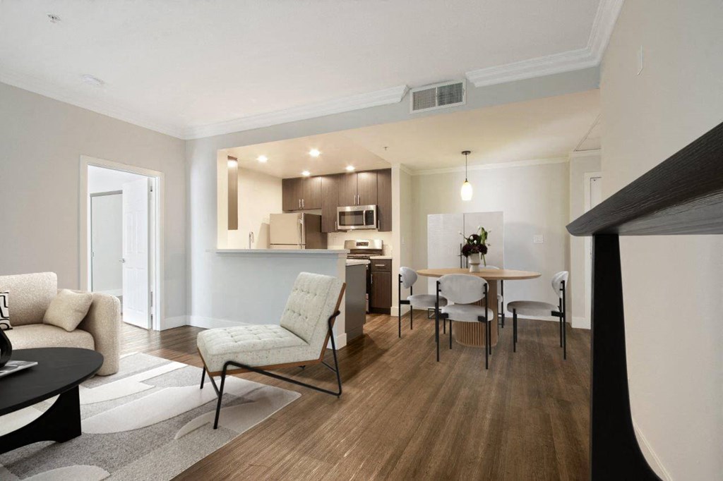 A modern living room with a dining area and a kitchen in the background at The Plaza Apartments, Los Angeles