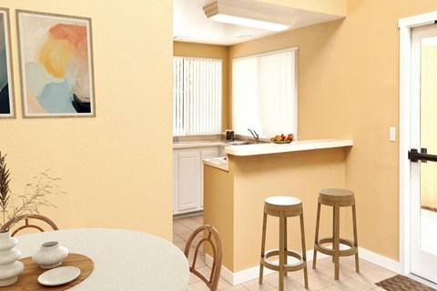 A kitchen with a bar stool and a table with a vase and a plate on it.