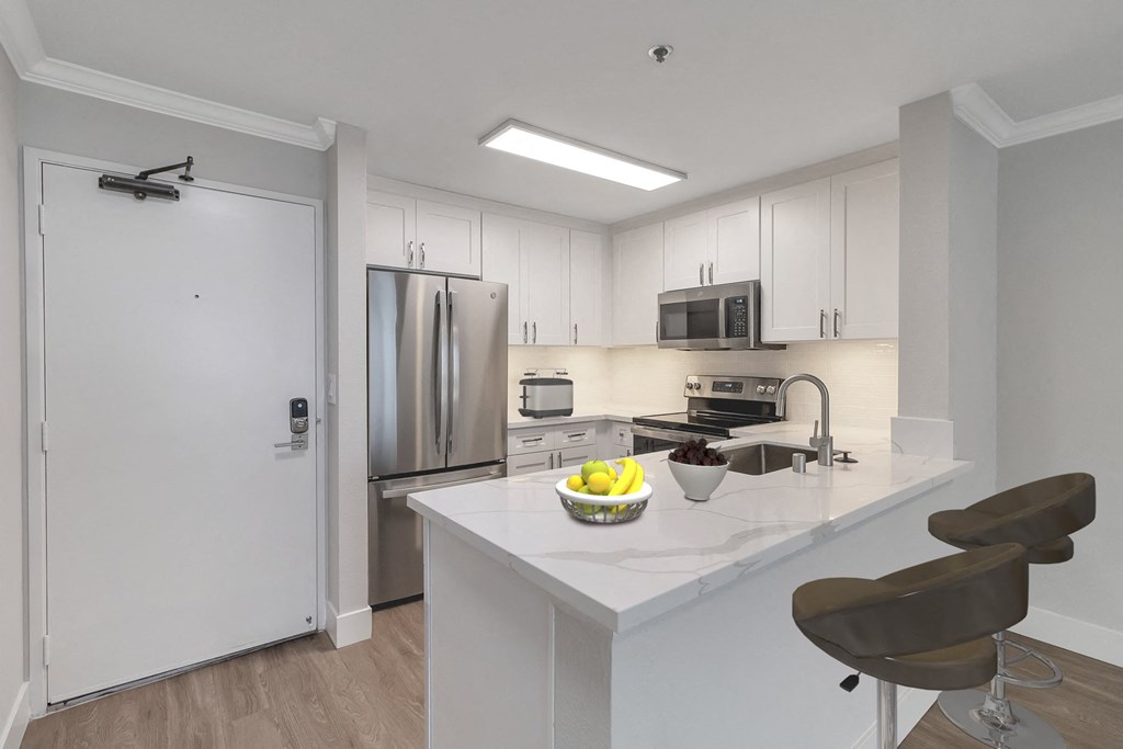 a kitchen with white cabinets and a white island with a bowl of fruit on it at Nobel Court, California, 92122