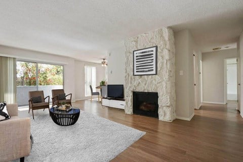 the living room has a stone fireplace and a rug