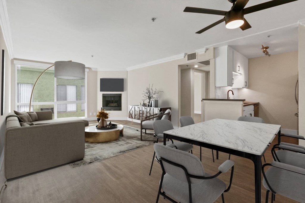 A modern living room with a grey sofa, a round coffee table, and a dining table with chairs at Rochester Apartments, California, 90024