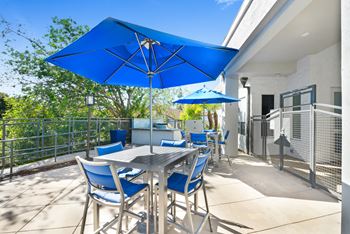 a patio with blue umbrellas and a dining table with blue chairs at Nobel Court, San Diego