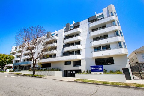 a white apartment building with a blue sign in front of it at The Kenmore Los Feliz, California