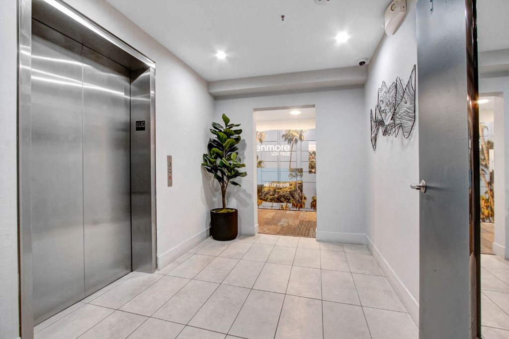 the entrance to a building with a metal elevator and a large plant in the corner at The Kenmore Los Feliz, Los Angeles, CA, 90027-4063