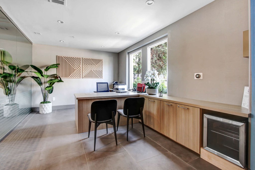 a home office with a wooden desk and two black chairs in front of a large window at Toluca Court, Toluca Lake, California