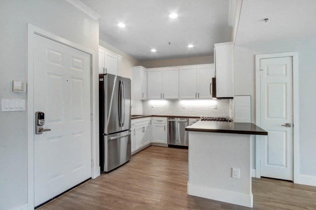 a kitchen with white cabinets and a stainless steel refrigerator at Toluca Court, Toluca Lake, CA