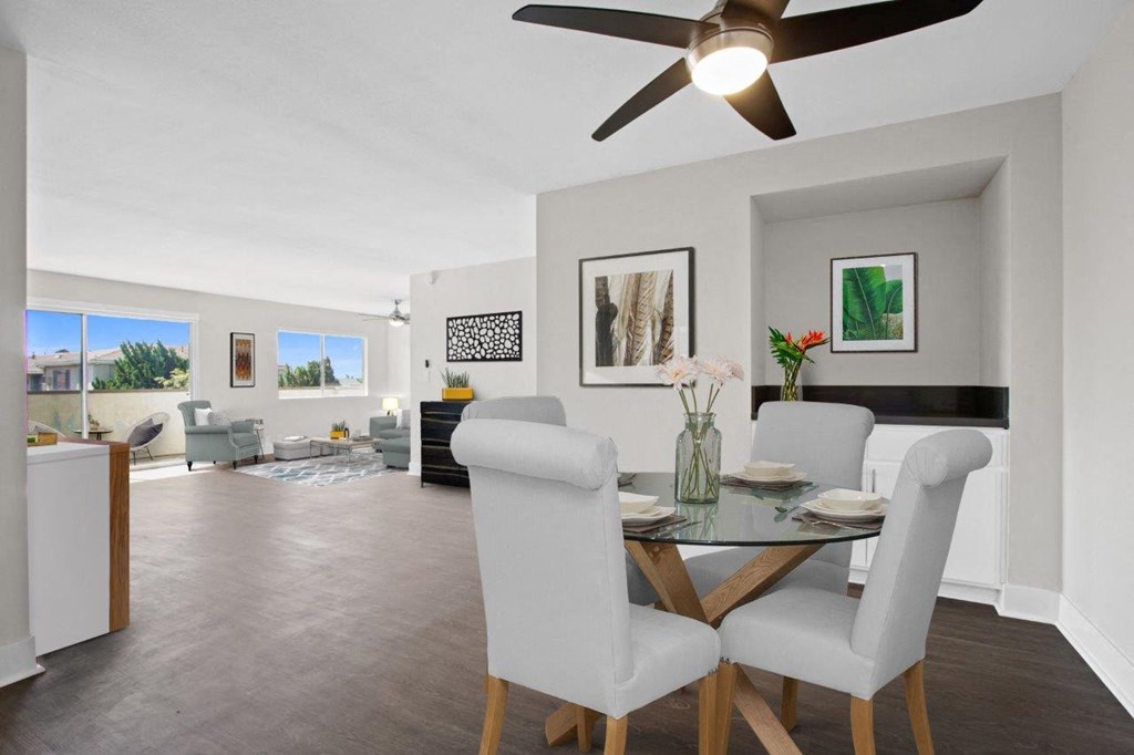 a dining room table with white chairs and a ceiling fan