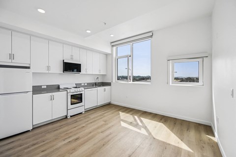 A kitchen with white cabinets and a wooden floor.