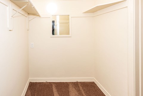 A small room with a brown carpet and a mirror on the wall.