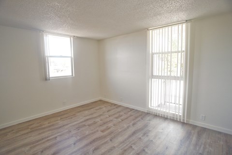 A room with vinyl flooring and two windows.