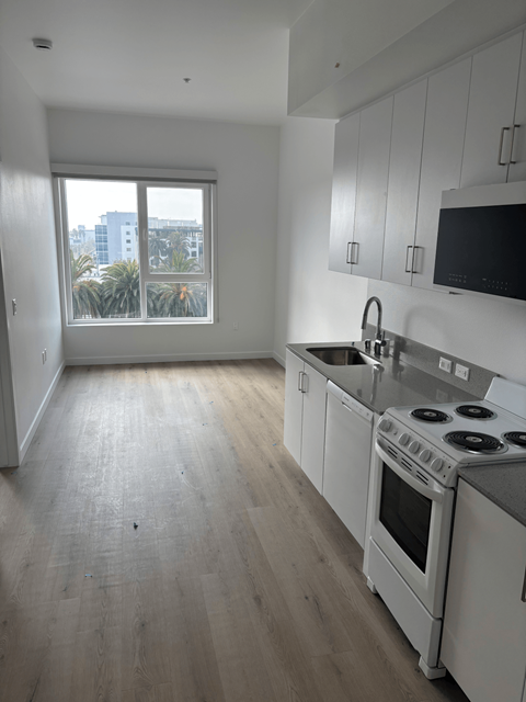 A kitchen with white cabinets and a stove top oven.