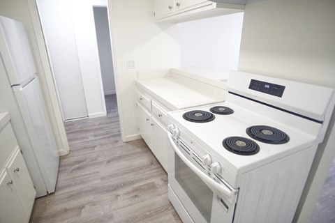 A white stove top oven with four burners and a stainless steel oven door.