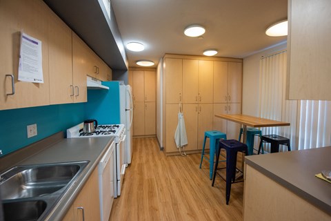 A kitchen with wooden cabinets and a blue wall.