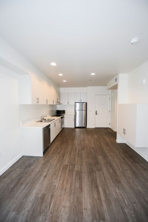 A kitchen with white cabinets and a wooden floor.