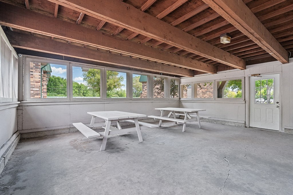 a patio with two picnic tables and windows in a house