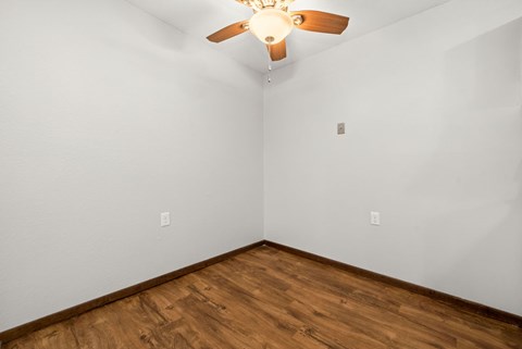 A room with a ceiling fan and wooden flooring.
