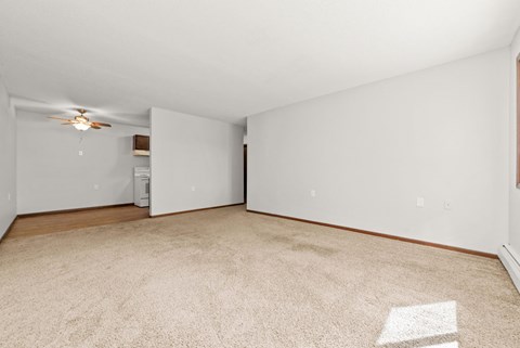 A room with a carpeted floor and a ceiling fan.