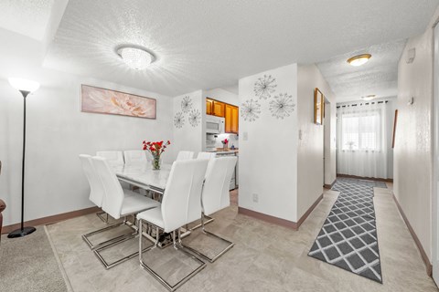 A dining room with a white table and chairs.