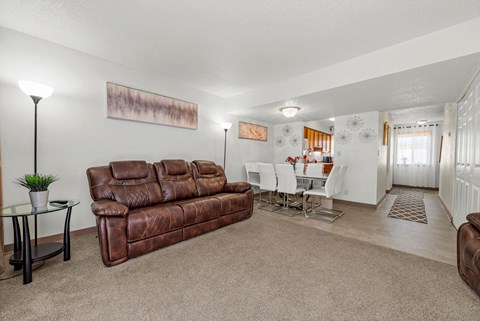 A living room with a brown leather couch and a glass coffee table.