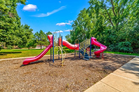 A playground with a red slide and a blue sky.
