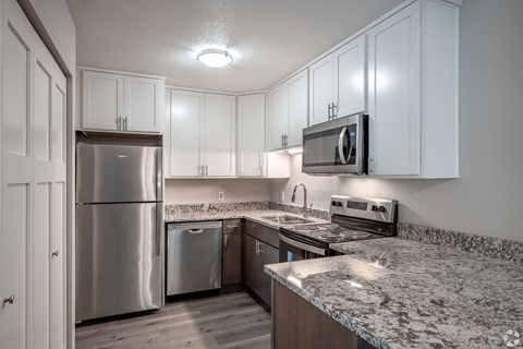 A kitchen with a granite countertop and stainless steel appliances.