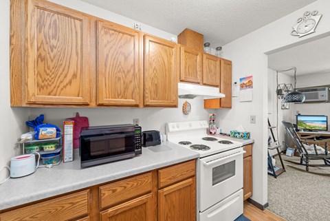 A kitchen with wooden cabinets and a white stove top oven.
