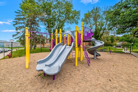 A playground with a purple slide and yellow poles.