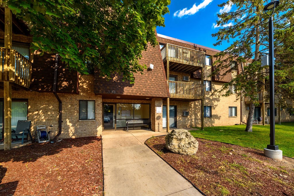 A large rock sits in the middle of a grassy area in front of a building.