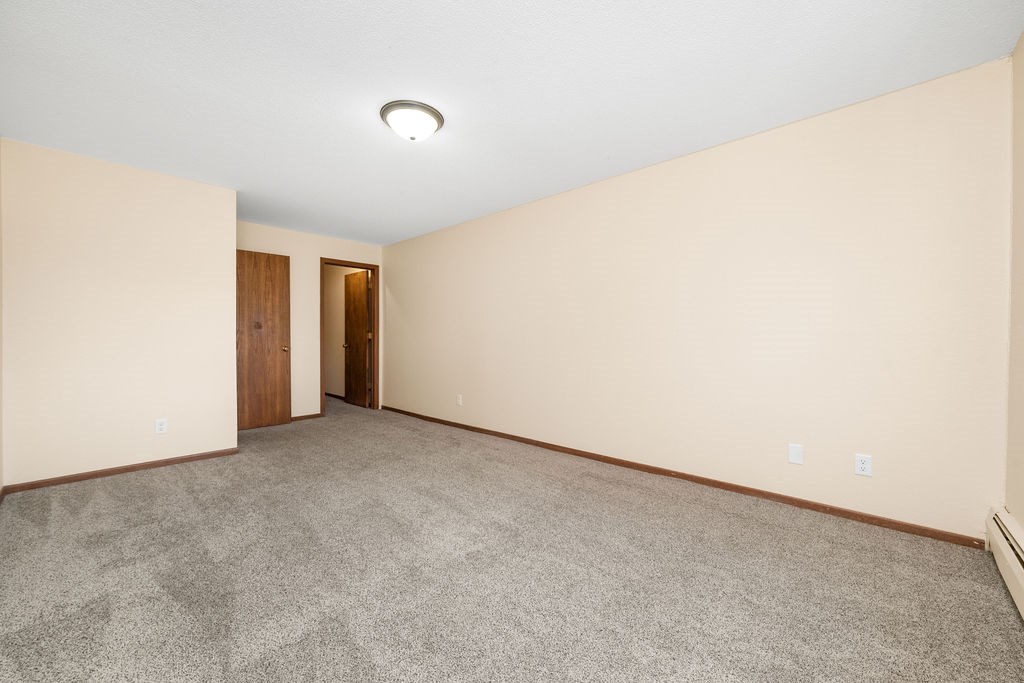 A room with a carpeted floor and two doors.