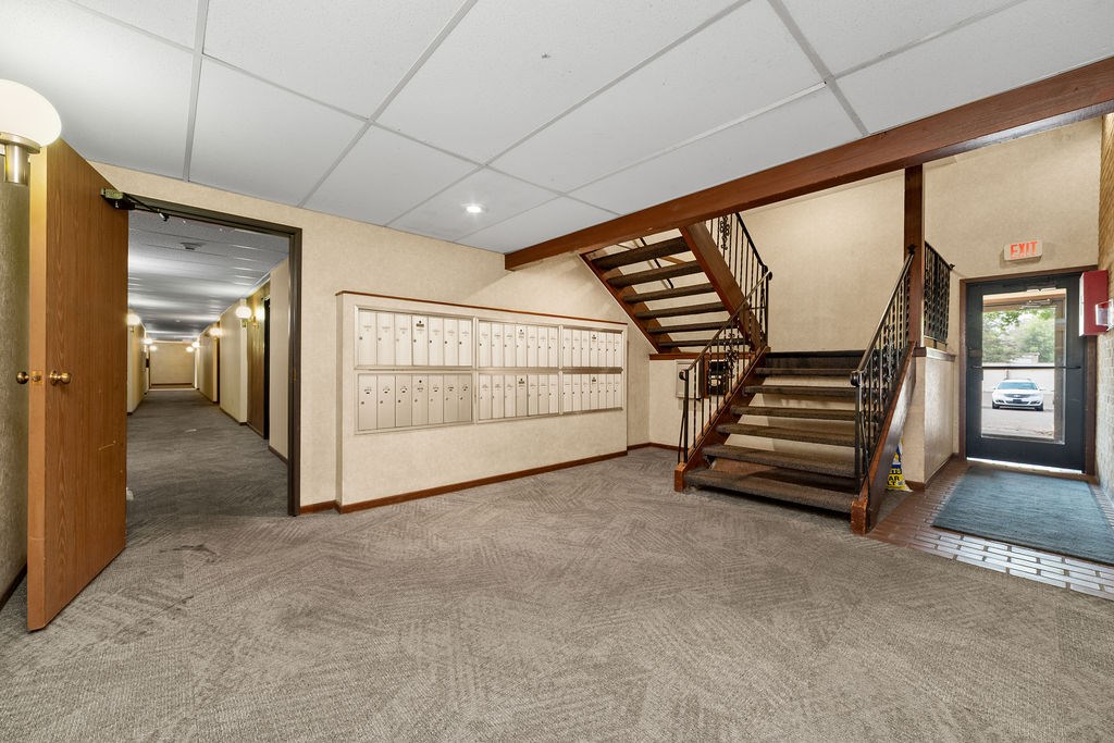 A hallway with a staircase and a calendar on the wall.